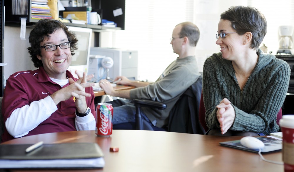 Co-editor Doug Hartmann, left, and managing editor Amy Johnson, right, discuss their magazine Contexts, while web editor Jon Smajda works in the background of their office in the Social Sciences Building on Friday. The goal of Contexts, which is owned by the American Sociological Association, is to make research more understandable.