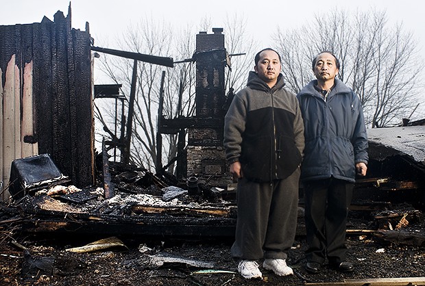 Changchua, left, and Hue Yang, right, stand in front of their house that burned down on January 28th. They are without insurance and lost nearly everything they owned in the fire. 