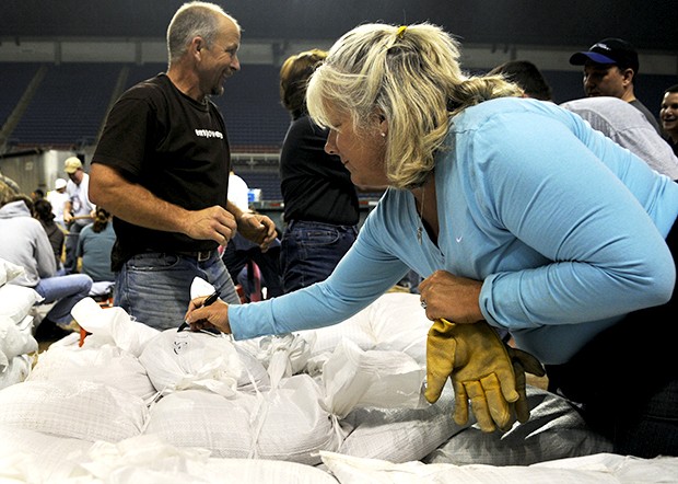 North Fargo resident and schoolteacher Cathy Speral writes messages on sandbags late Thursday evening at the Fargodome. Speral said she hoped it would boost the spirits of volunteers working on the front lines.