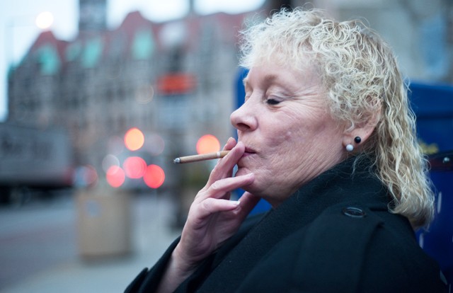 Chiri Litz, 58, inhales her cigarette at the bus stop near 6th and Wabasha in St. Paul while waiting for the Eastbound 64 to get her flu shot Friday morning. While smoking Chiri jokingly says, Ive set a date to stop smoking. The year 2080, because then Ill be dead.