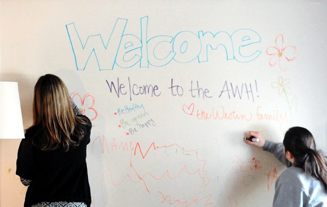 Willings, left, and Fox write welcome messages Sunday on the common room white board to the eight new residents.