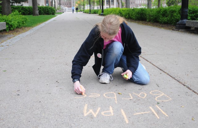Mathematics senior Melissa Checky chalks announcements about IT Week on Sunday in the Northrop Mall area.