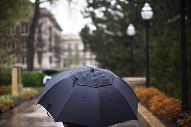 A student uses an umbrella to hide from the rain.