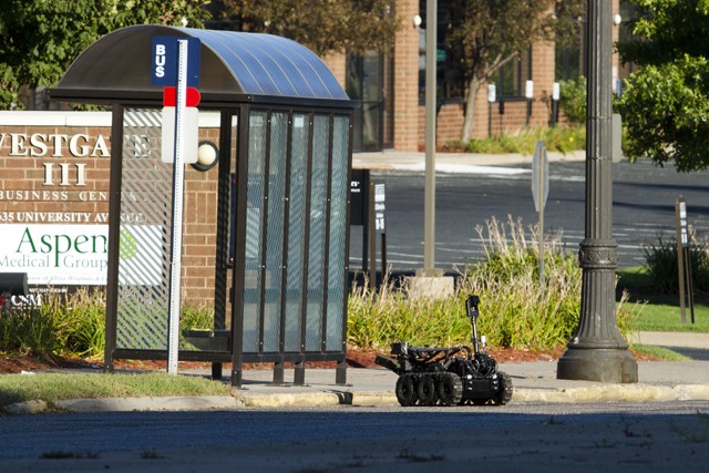 A St. Paul bomb squad robot removes the suspicious package from a bus stop Saturday near University Avenue West and Barry Street.