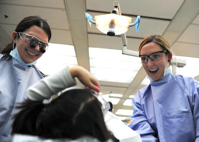 Dental students Kacie Woodis, left, and Megan Mulligan, right, prepare Andrea Schyumn, 5, for an X-ray during Give Kids a Smile Day at Moos Tower on Saturday. The event, which is aimed at providing free dental care to children of low-income families, is practiced annually at clinics all over the country.