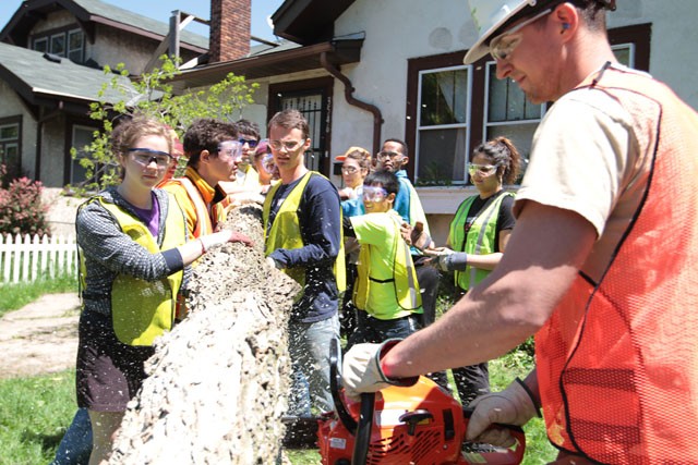 Student volunteers work together to clean up fallen trees on Thursday in North Minneapolis.