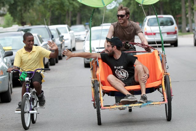 Connor Lynch high fives a passer by Monday while Stormy from Shottyz Pedicab and Bike Repair takes him for a spin in South Minneapolis.

