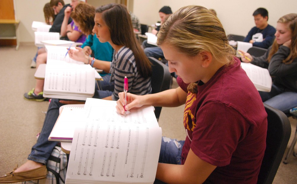 Sophomore Courtney Comar writes music notes Monday as her teacher plays the piano during a sight-singing class.