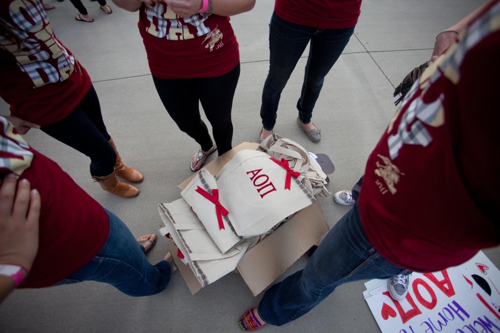 Alpha Omicron Pi members stand around a box of welcome bags for new recruits. 