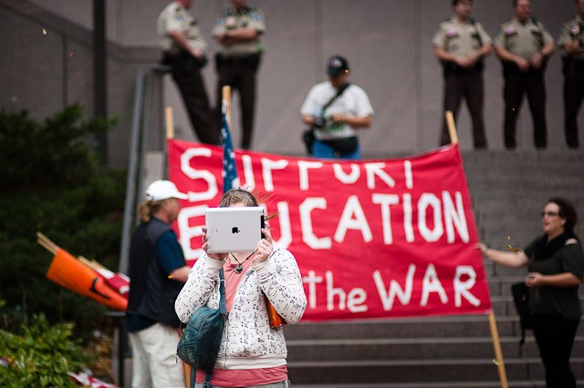 A woman uses her iPad to record video of protesters Friday at the Hennepin County Government Center.