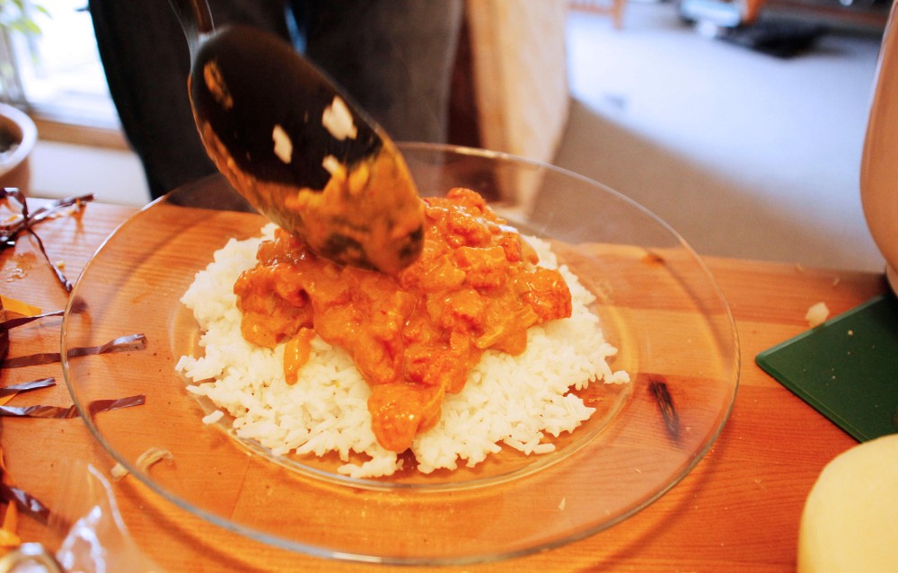 A tomato curry sauce tops a plate of rice. This sauce includes onions, tomato, peanut butter, orange juice and milk, among a few other ingredients that college students can commonly find in fridge.