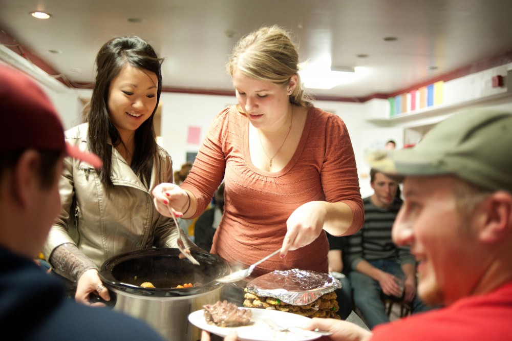 Junior Ashley Kipka, right, and her assistant Ashley Swenson, left, serves her roast to the seniors of Alpha Gamma Rho as part of their sweetheart week activities on Thursday at the fraternitys house.