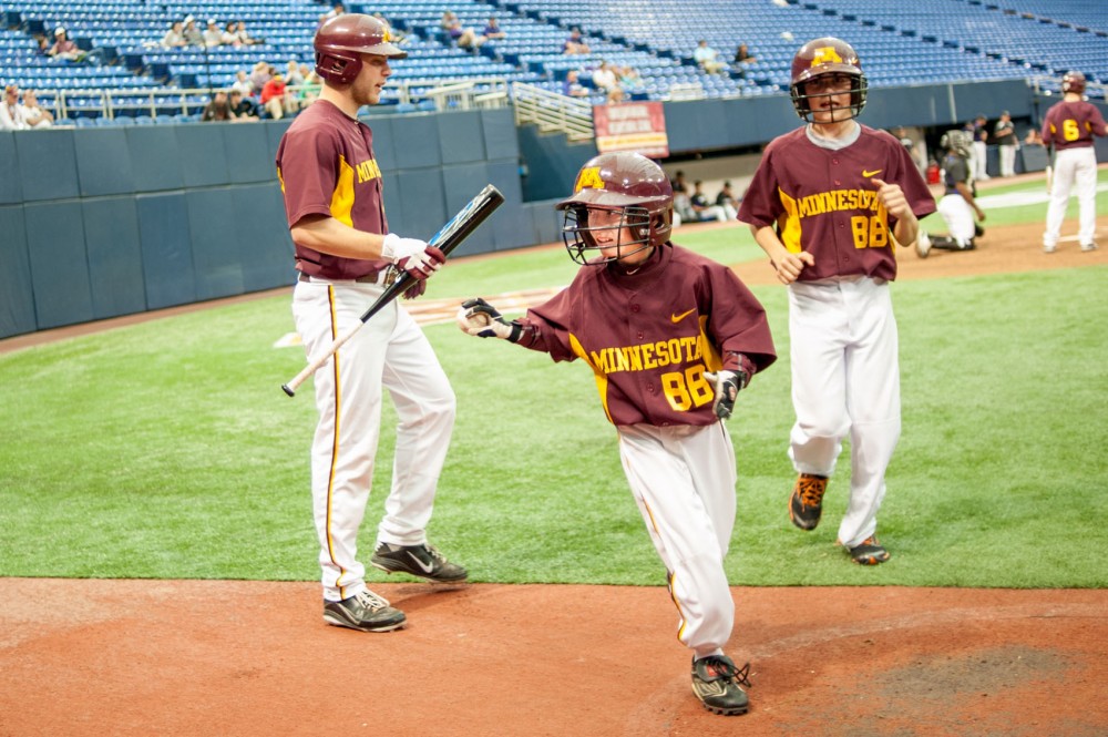 Gophers bat boy Griffin Ruiter grabs a ball from catcher Kurt Schlangen on Saturday at the Metrodome.  His duties include collecting stray bats and balls and inspecting them for ware.