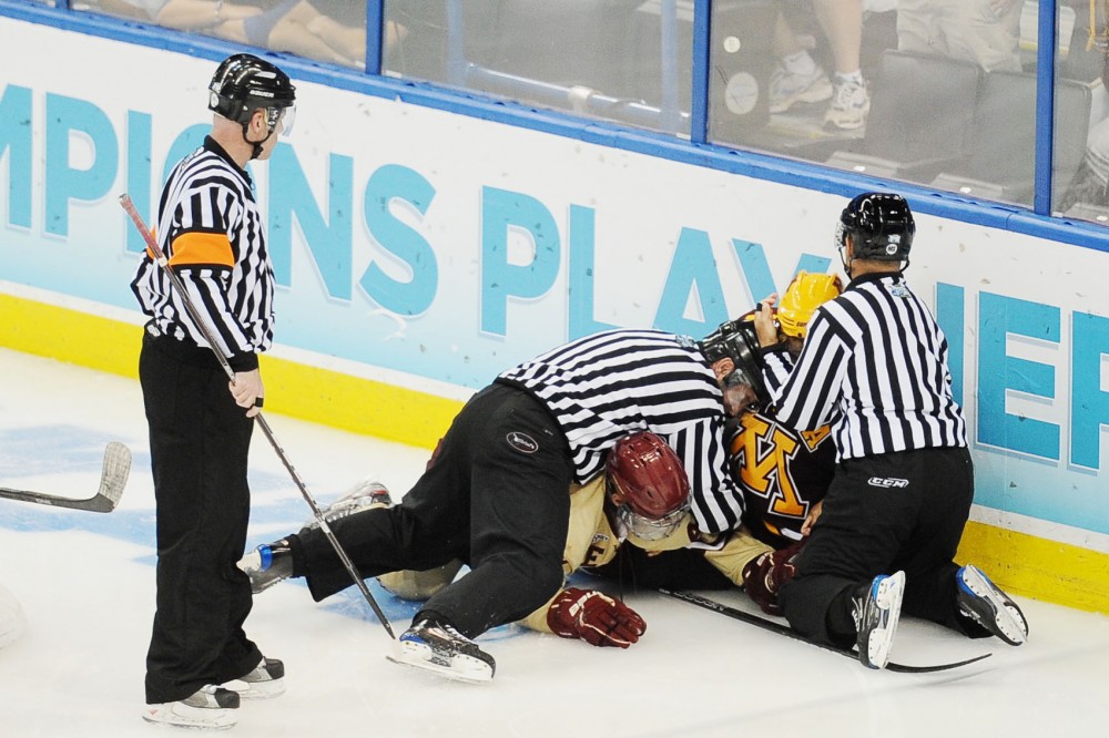 Gophers forward Zach Budish and Eagles defenseman Tommy Cross fight behind Boston College’s net on Thursday in Tampa, Fla. Boston College defeated Minnesota 6-1.