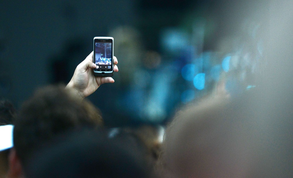 A fan uses a cell phone to record Tool performing at Rivers Edge Music Festival in St. Paul, Minn.