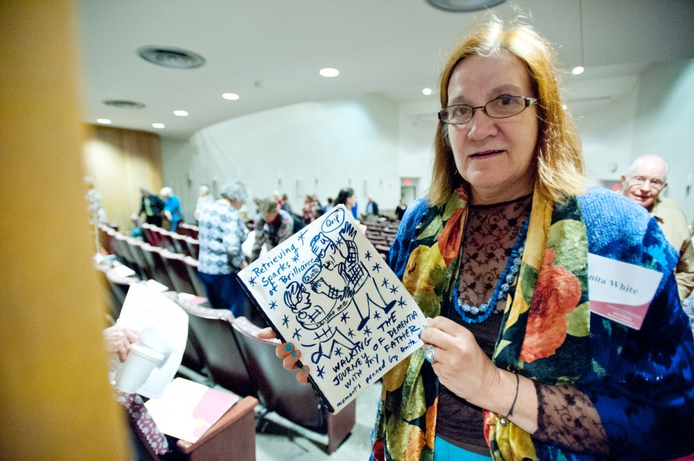 Anita White holds the journal she has created while caring for her 87-year-old father, who has dementia, at the Mayo Auditorium on Saturday. White was inspired to journal from her experiences dealing with her father’s memory loss.
