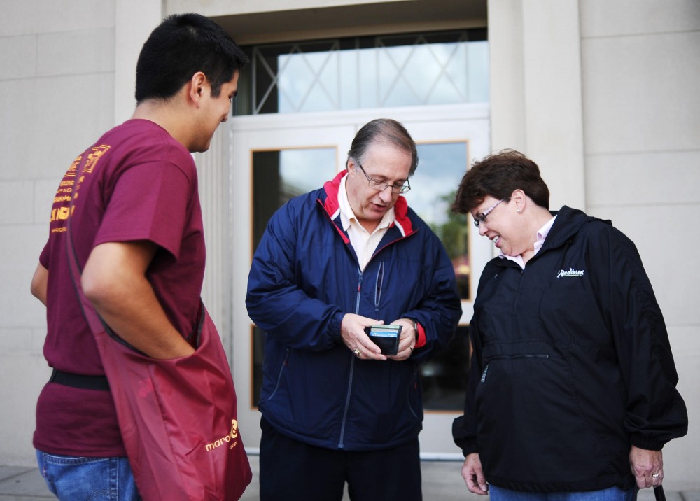 Student Unions and Activities member Eder Castillo solicits a $2 donation from University alum Dave Goebel and his wife Lynne towards the construction of the Goldy statue on Friday in front of Coffman Union.