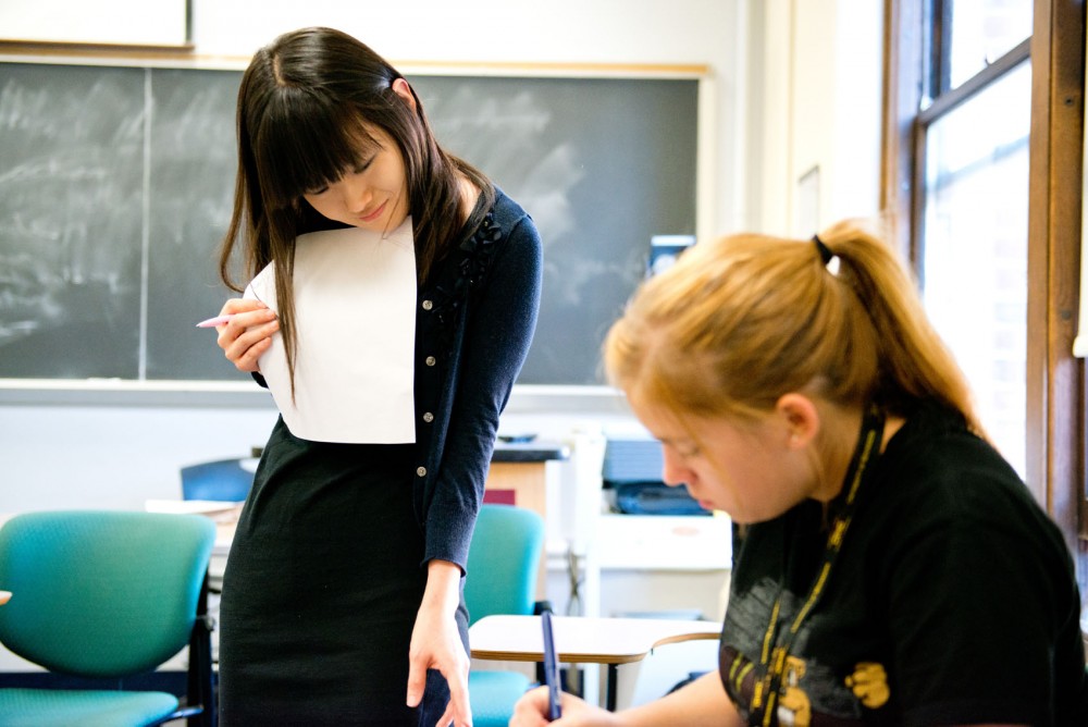 Instructor Hyeryung Hwang helps a student during a group discussion in a University writing class in Lind Hall.