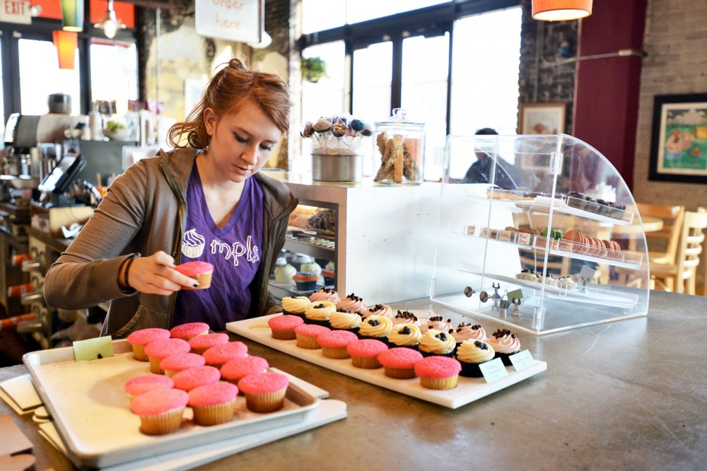 Employee Ashley Krueger arranges cupcakes to be put in the display case Wednesday morning at Cupcake on University Avenue Southeast. 