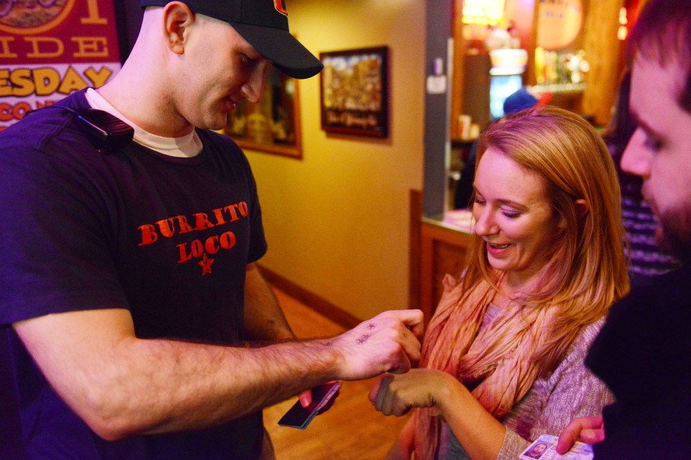 Nick Pouladian, left, stamps Laura Rickes hand at Burrito Loco on Friday night. Speaking with each guest helps maintain security in the Dinkytown area.