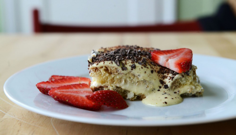 A simple tiramisu with chocolate shavings on top and strawberries on the side. 