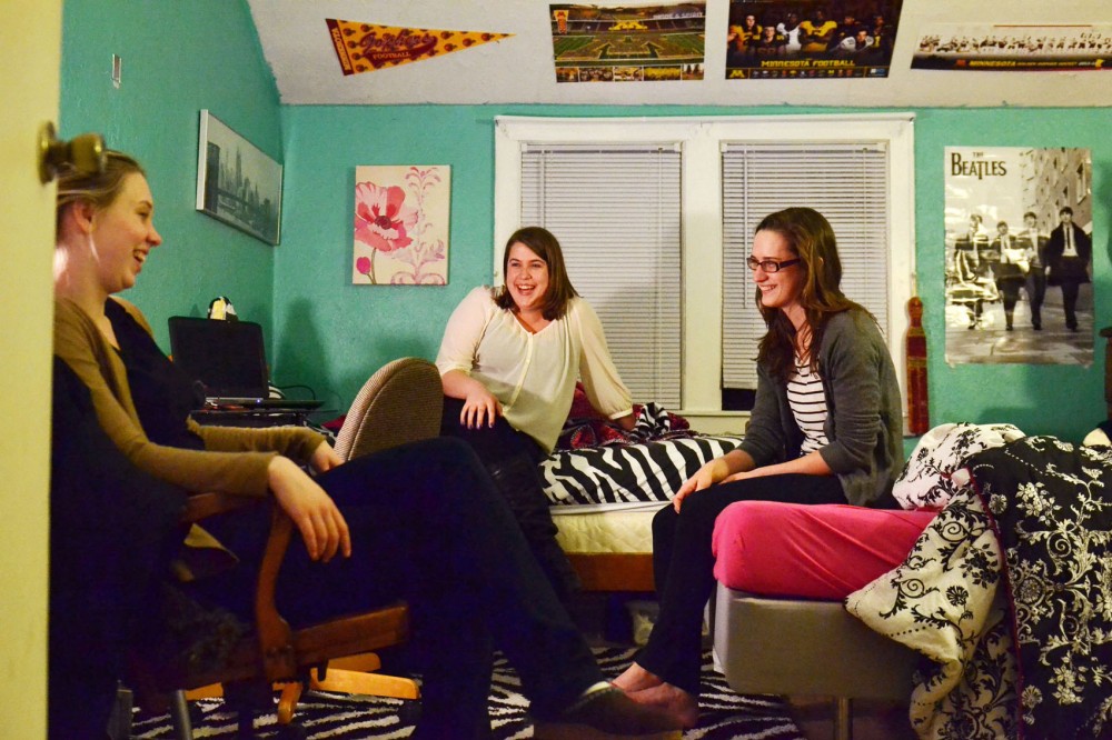 Roommates Maria Finsness, left, Maddie Hansen, center, and Emma Reese relax in one of their rooms Sunday, March 10, 2013, in their Dinkytown home. The three roommates share the home with 11 other people and said they consider rent very affordable.