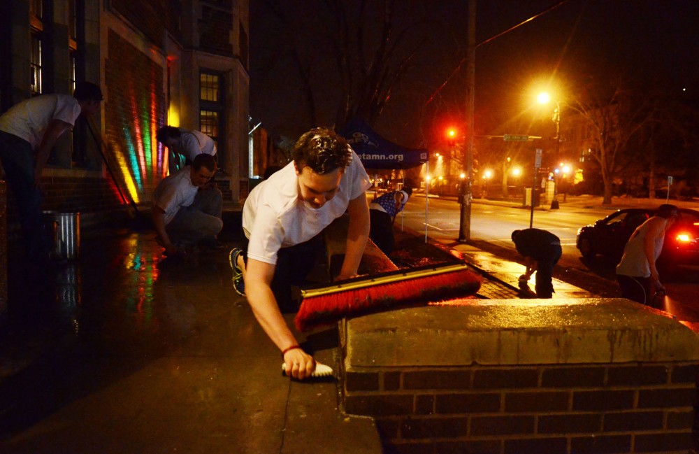 Beta Theta Pi members clean pie off their front steps after their Beta Theta Pies event.