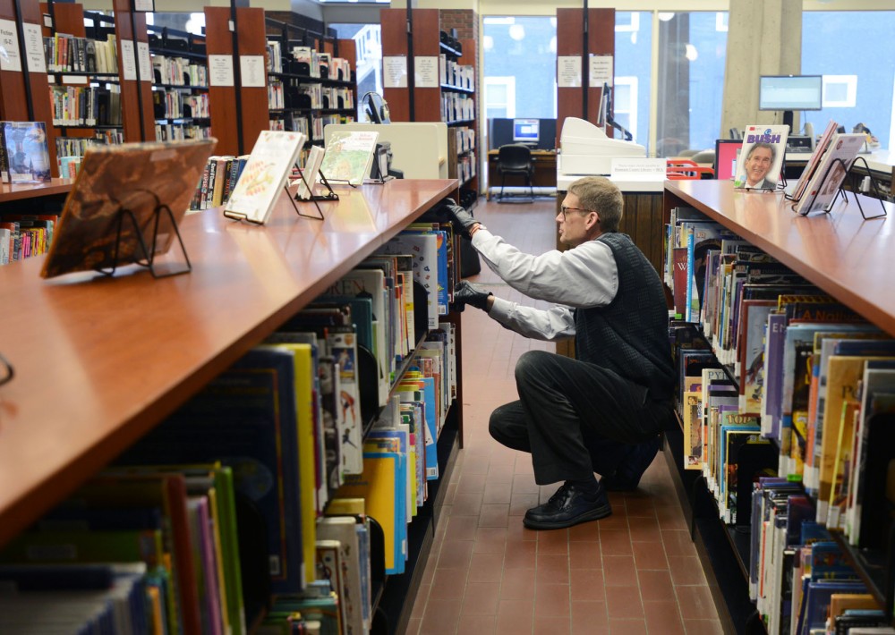 Public service assistant Wade Huber re-shelves books at the Southeast Library in Dinkytown on Thursday, April 18, 2013. 