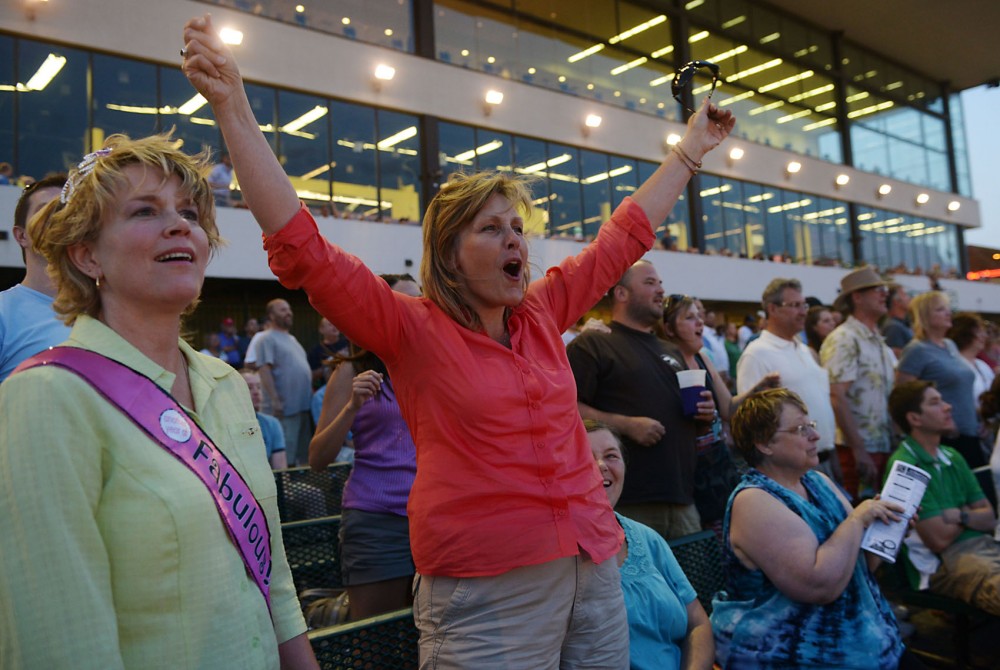 In a close finish, Sarah Louise Benidt-Grave, left, watches her horse lose as her friend, Dodie Harris, celebrates her win at Canterbury Park on Friday, July 12, 2013. The women spent the night at the race track celebrating Louise Benidt-Graves birthday.