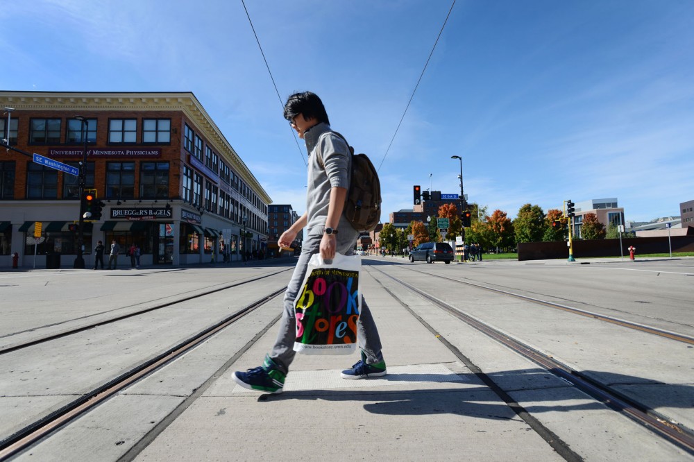 A pedestrian crosses the light rail tracks on the intersection of Oak Street and Washington Avenue on Monday, Oct. 7, 2013. The line is slated for completion in 2014.