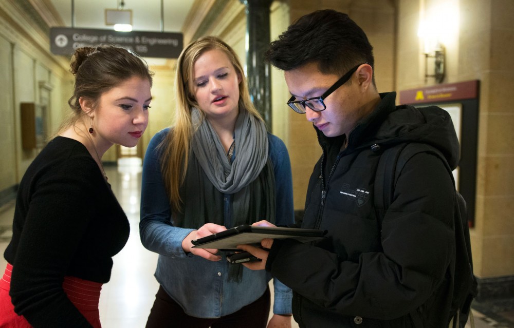 Freshmen MSA members Katerina Paone and Johanna Christner help clarify a question on a survey for freshman Qingkang Cao at Walter Library on Thursday afternoon. MSA members poll students weekly about different topics regarding the University.