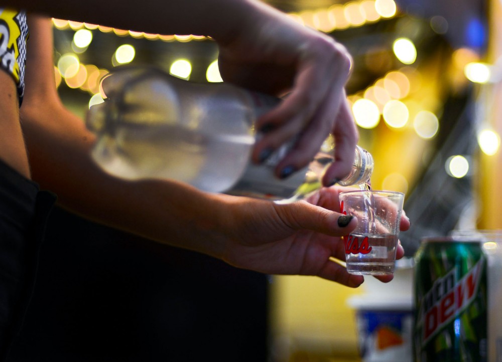 Before going out on Friday night, a freshman pours a shot in a dorm room.