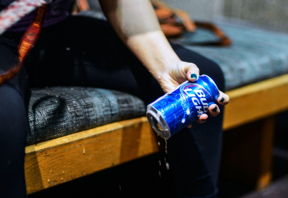A student shotguns a beer in a dorm lobby on Friday night. The student shotgunned the beer as part of a neknomination, an online drinking game.