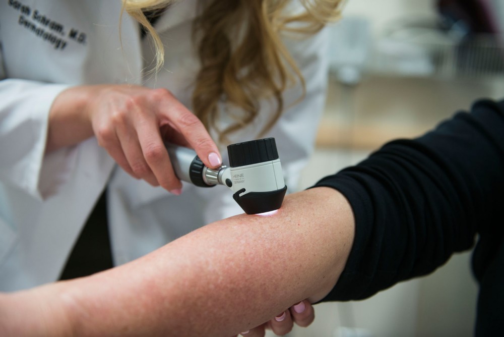 M.D. Sarah Schram demonstrates an examination for possible melanomas at the Dermatology Clinic on Monday.