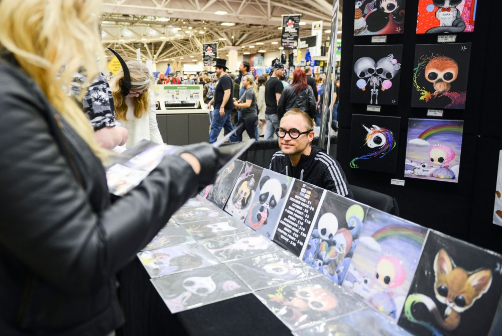 Artist Michael Banks exhibits his art work while Minneapolis Comic Con attendees browse at the Convention Center on Saturday. Wizard World held its first Minneapolis Comic Con this weekend. 
