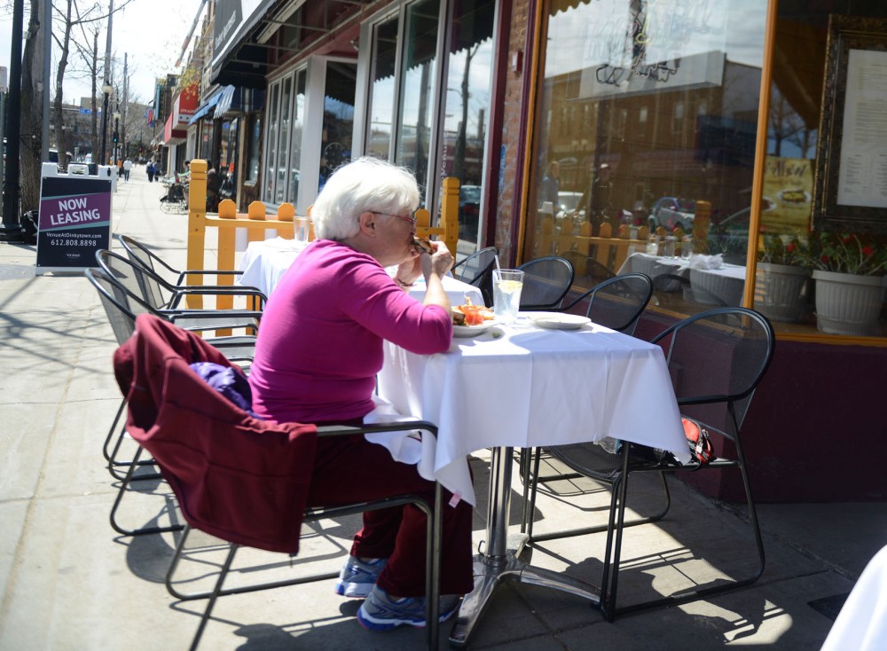 Barbara Saunders eats outside of Kafe 421 in Dinkytown on Sunday. City lawmakers are considering expanding outdoor marketing and sales for area businesses. 