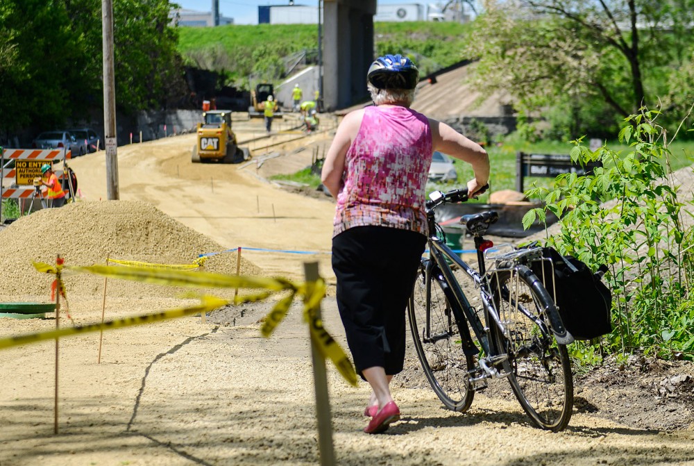A woman walks her bike past an area where a new bike trail will be built, Thursday afternoon. The new bike trail is the most expensive per mile that the city has ever built and will connect the University to downtown Minneapolis.