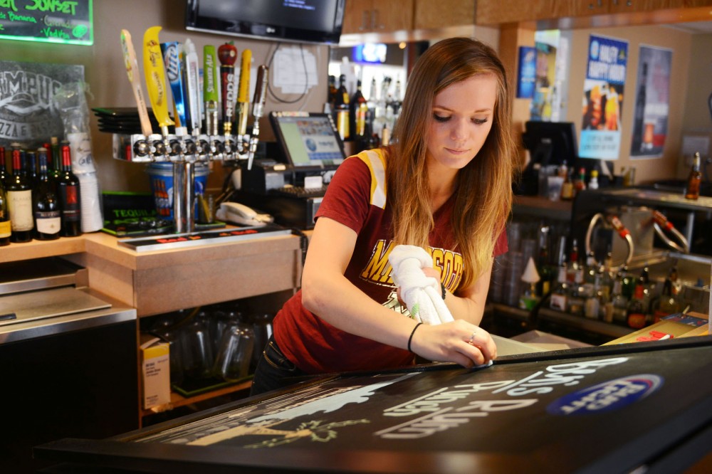Psychology and criminology junior Kayla Latarte writes specials on a board Friday at Campus Pizza, where she is a bartender. 