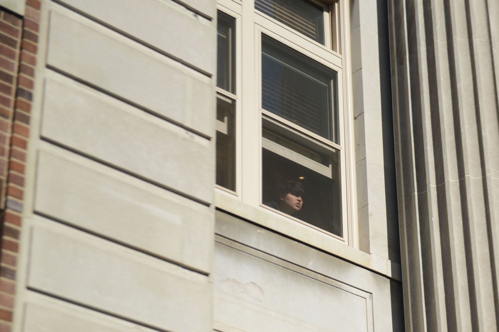 An activist shouts down to the crowd of protestors from the windows of Morril Hall on Monday afternoon.