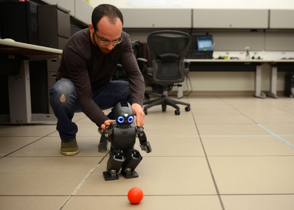 Ph.D. candidate Dimitris Zermas plays soccer with Darwin the Humanoid Research Robot in Walter Library on Friday, April 3rd.
