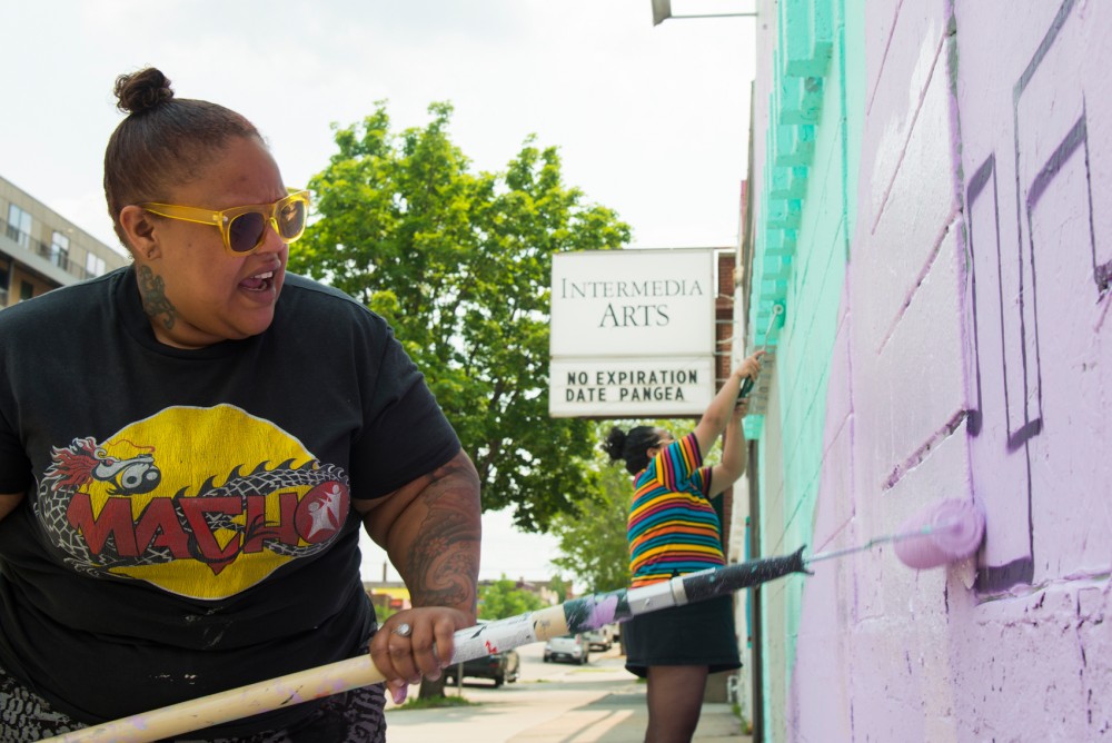 Joy Spika, left, and Leilani Mendoza paint the outer walls of Intermedia Arts in Uptown Minneapolis on Monday afternoon. The mural is part of the B-Girl Be exhibit, which opens on Saturday.