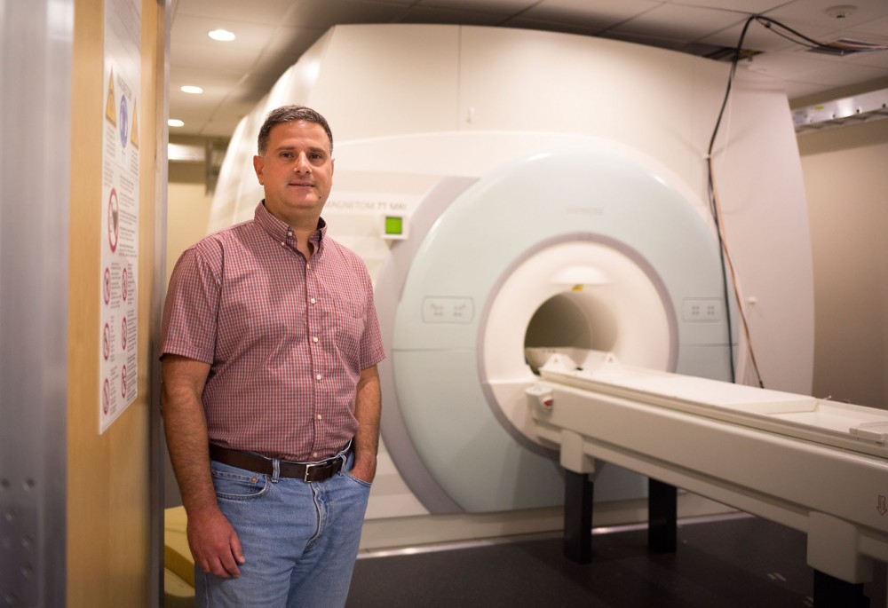 Dr. Noam Harel, an associate professor in the Universitys departments of Radiology and Neurosurgery, poses in front of a 7 Tesla MRI scanner in the Center for Magnetic Resonance Research on Monday. The 7 Tesla model has the ability to capture highly accurate images of the brain, which aids in the success of deep brain stimulation surgery.