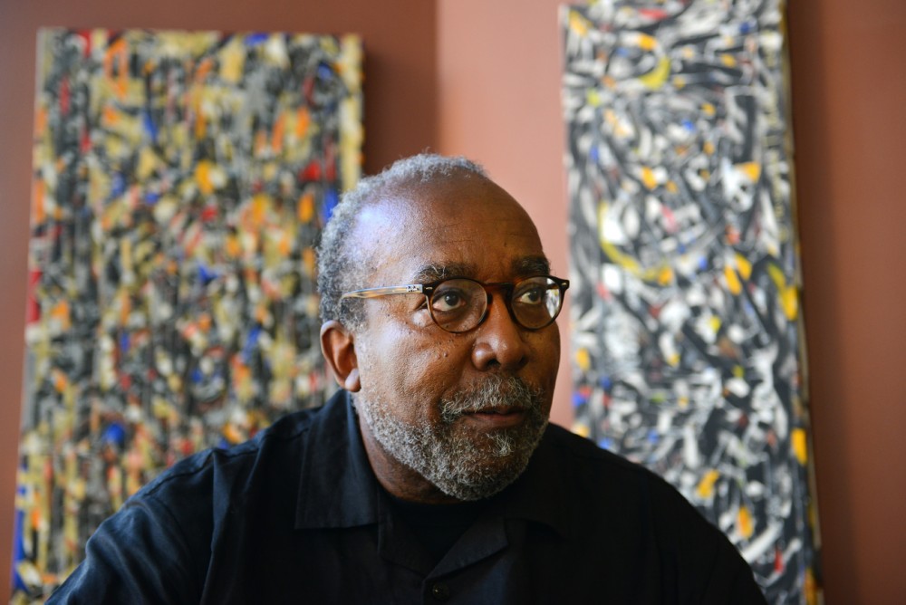 Twin Cities artist Ta–coumba T. Aiken poses with a selection of his rhythm paintings in the Show Gallery Lowertown on Tuesday. Aikens exhibition opened to the public last night, November 4. 