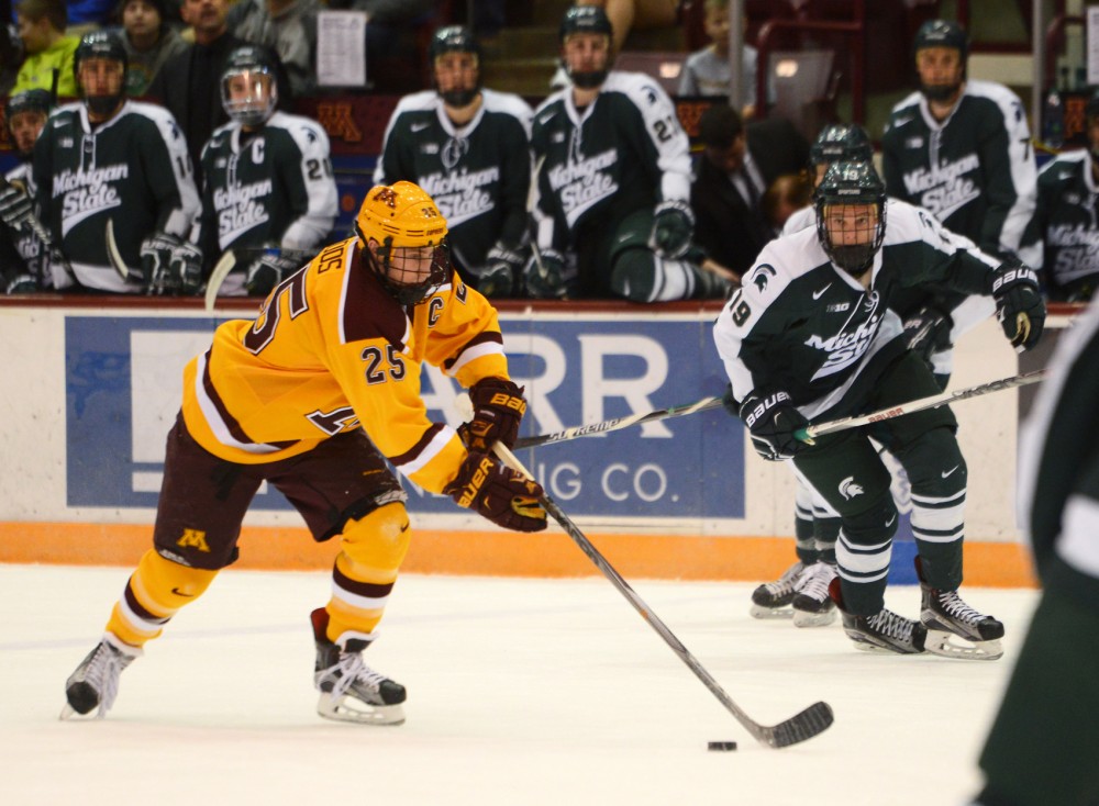 Gophers forward Justin Kloos drives the puck against Spartan defenders at Mariucci Arena on Saturday. Minnesota swept Michigan State to close the series with a final score of 3-1.