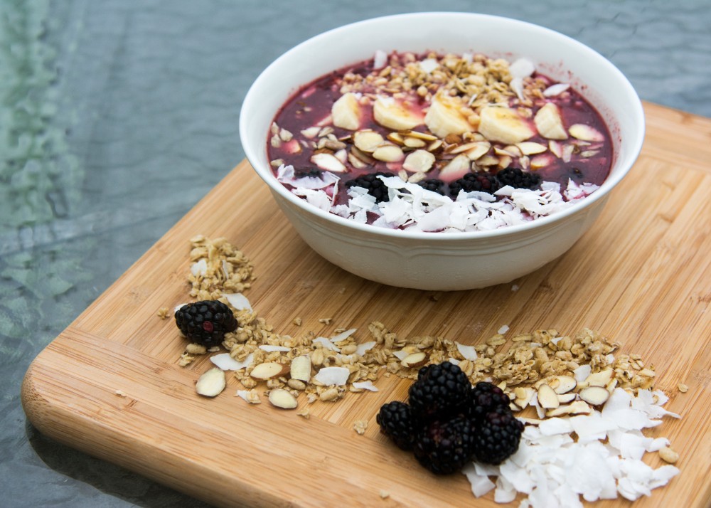 An acai bowl with shredded coconut, almonds, blackberries, banana and granola.