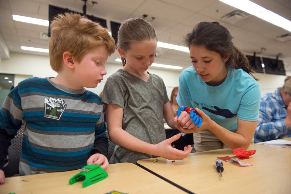Six-year-old John Donohoo, left, and Kelly Hannon assemble a 3D printed prosthetic hand with cousin Elizabeth Moy, a member of Engineering World Health. The student group hosted Giving a Hand, an event at which attendees built prosthetic hands for children in Honduras and Tanzania, in Moos Tower on Saturday.