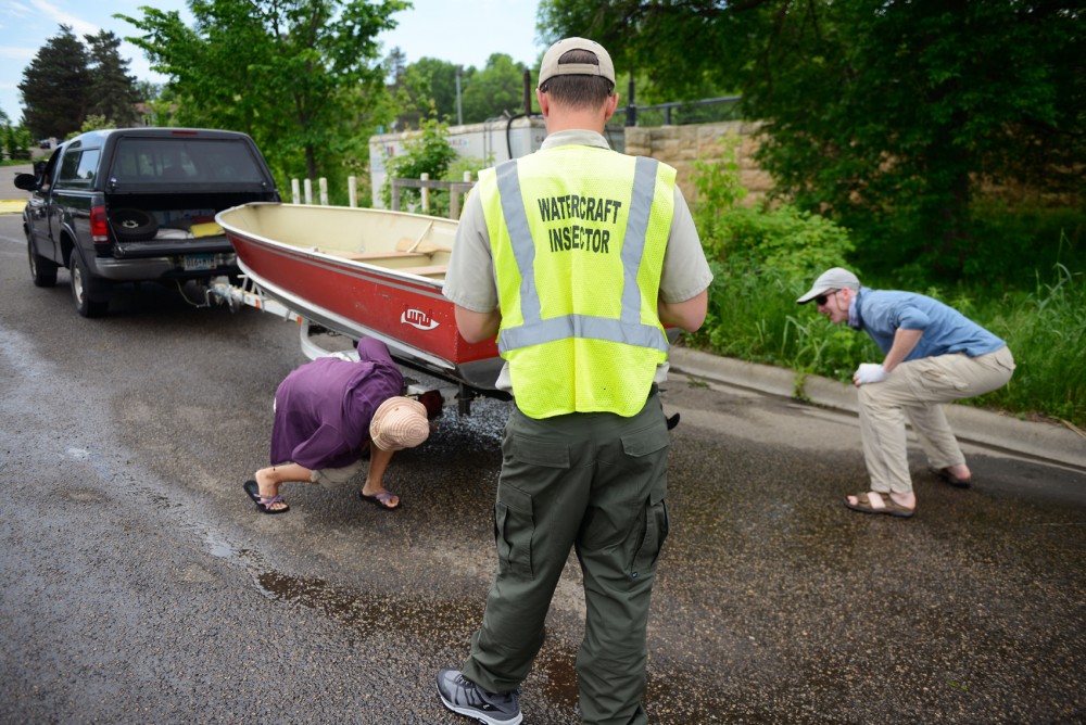 Watercraft Inspector Jack Kronberg, along with the boat owners, inspect a boat for invasive species before it enters the water at Grays Bay on Lake Minnetonka on Memorial Day.