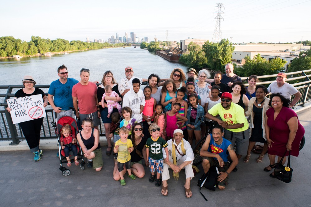 Members of the North Minneapolis community come together on the Lowry Avenue Bridge in unity against Northern Metal Recycling, as seen in the distance behind them on the evening of June 9. A report by the Minnesota Pollution Control Agency that lists the neighborhood surrounding the facility as the citys highest levels of lead poising and asthma hospitalizations, and points to the recycling facility as a leading cause in the issue.  