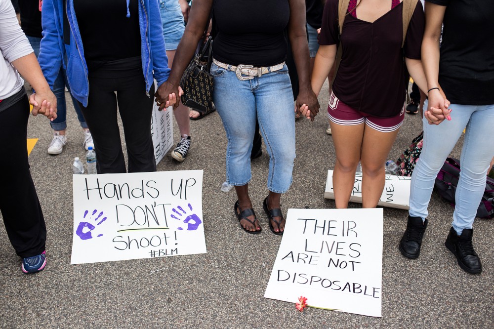Protestors held hands during a group prayer outside of the St. Anthony Police Department, where they rallied demanding justice for Philando Castile on Sunday, July 10.