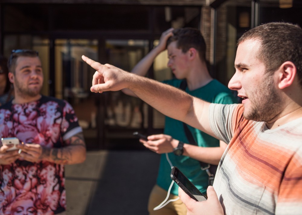 Left to right, Sam Hirsch, Cian Newport and Tyler Blase stop for a moment while playing Pokémon Go in front of Sencha Tea Bar at the Stadium Village Mall on Washington Ave. on July 18. Sencha Tea Bar is one of several restaurants that are offering promotions to help attract users of Pokémon Go. 